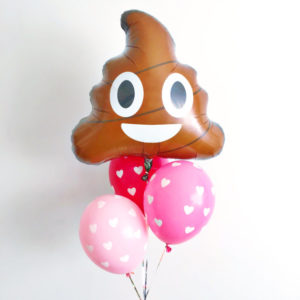 A bunch of Quinceanera-themed balloons, including one with a poop face on it.