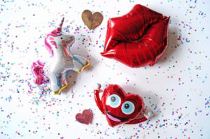 A Quinceanera-themed image of a stuffed toy with heart-shaped balloons and a unicorn.