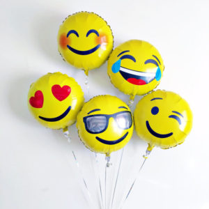 Quinceanera themed image with emoji foil balloons and a bunch of balloons with smiley faces on them