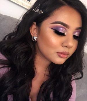 A woman with long black hair and purple eyeshadow, ready for her Quinceanera celebration.