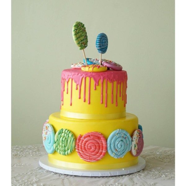 A Quinceanera themed sugar cake, featuring a yellow cake adorned with candy and lollipops on top