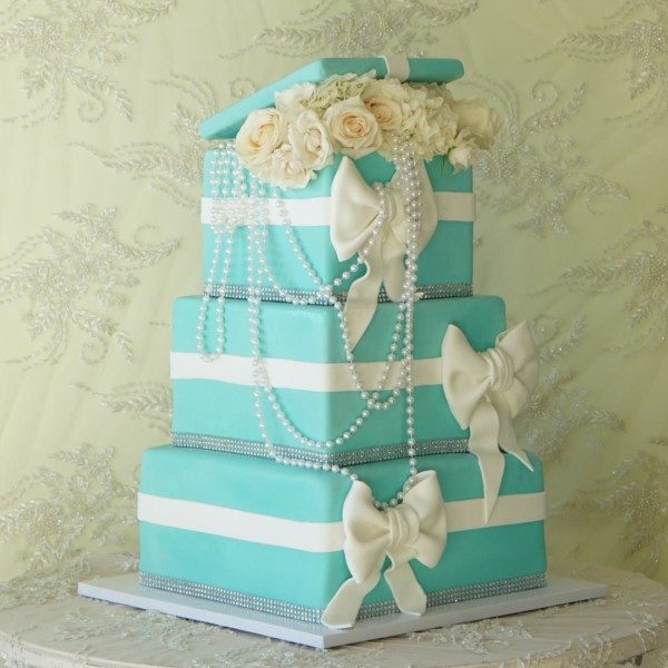 A Quinceanera cake, a three tiered cake with pearls and flowers on top