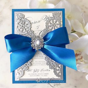 A blue and silver Quinceanera invitation with a ribbon table and a bow.