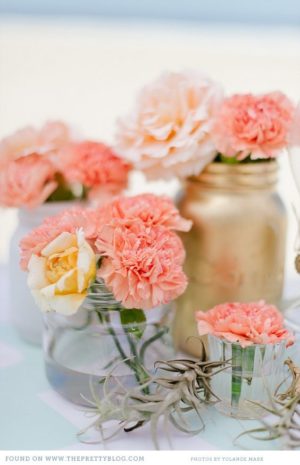 Quinceanera table decoration with a group of vases filled with pink and yellow flowers