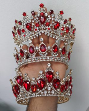 A hand holding a red and white crown, symbolizing jewellery for a Quinceañera