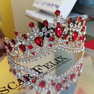 A woman holding a red crystal crown, adorned with beautiful Quinceanera jewellery
