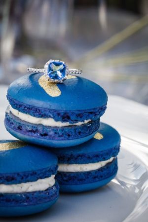 A stack of blue macarons with a diamond ring on top, perfect for a Quinceanera invitation.