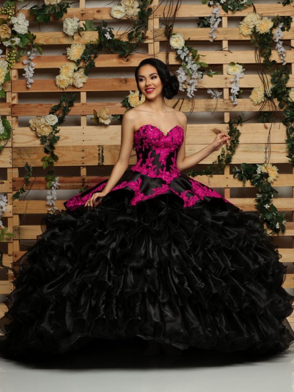 A woman in a black and pink gown Quinceañera dress posing for a picture.