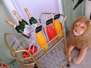 A Quinceañera dog sitting next to a lion statue with a cart of drinks