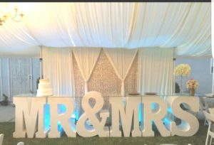 Quinceanera window treatment in a wedding reception featuring a large Mr and Mrs sign