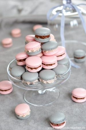 A glass plate filled with pink and grey macarons in a Quinceanera color scheme