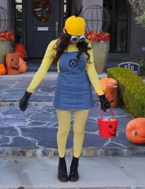 A woman dressed as a minion holding a bucket, wearing a Quinceanera costume