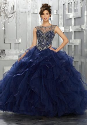 A woman in a blue Quinceanera gown standing in front of a chandelier, showcasing the beautiful fall Quinceanera colors.