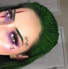 Quinceanera: Joker, a woman with green hair and purple makeup, gives an aesthetic twist to her maquillaje.