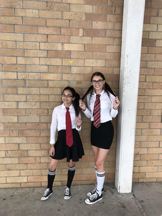 Quinceanera costume idea of mathlete vs athlete. Two girls in Quinceanera dresses standing next to a brick wall.