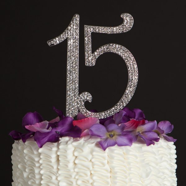 A close up of a Quinceanera cake with flowers on it, and a doll topper