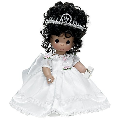 A precious moments doll with black hair wearing a white dress and tiara in a Quinceanera theme.