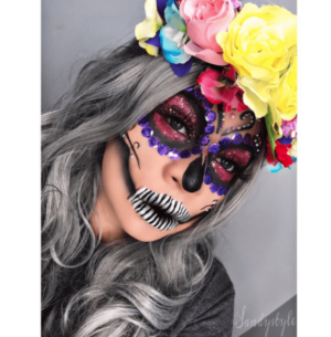 A woman wearing a masque headpiece and a flower crown on her head, representing a Quinceanera celebration.