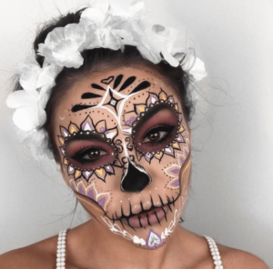 A woman with a sugar skull make-up on her face, with a Quinceanera theme