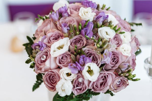 A Quinceanera flower bouquet in a vase filled with purple and white flowers