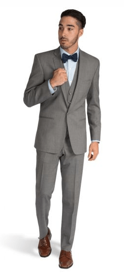 A man in a standing blazer, wearing a gray suit and bow tie, at a Quinceanera celebration.