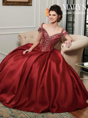 A woman in a red dress sitting on a couch, wearing a Quinceanera gown