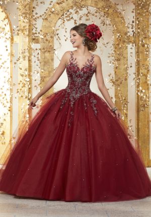 A woman in a red Quinceanera gown standing in front of a gold wall