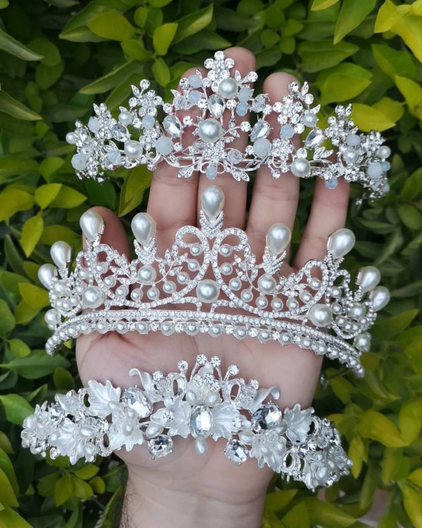 A Quinceanera image featuring a floral design bouquet and a hand holding a tia with a bunch of pearls on it