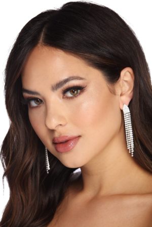 A woman wearing a white top and earrings, with beauty earring