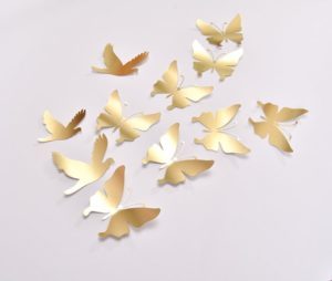 A Quinceanera themed image featuring a petal Wall Decal and a white table topped with lots of gold butterflies.