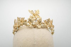A stunning gold crown adorns a mannequin head, creating a regal jewelry piece for a Quinceanera celebration.