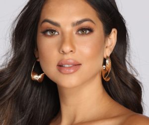 A beautiful woman with long brown hair wearing gold hoop earrings and stunning Quinceanera jewellery