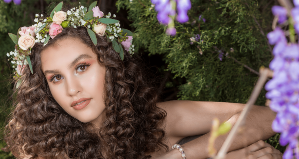 A beautiful woman with curly hair wearing a flower crown surrounded by floral design