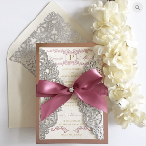 A close up of a lilac Quinceañera invitation with a pink ribbon