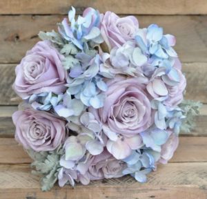 A Quinceanera bouquet of blue and purple hydrangea flowers on a wooden table