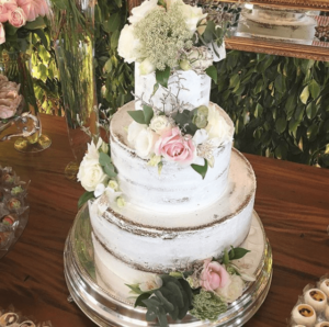 A floral design three-tiered Quinceanera cake on a table.