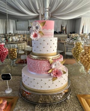 A Quinceanera cake with three tiers, decorated with pink and gold accents.