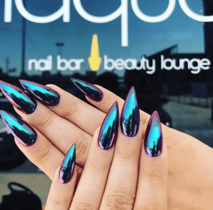 A hand with a black and purple Quinceanera manicure