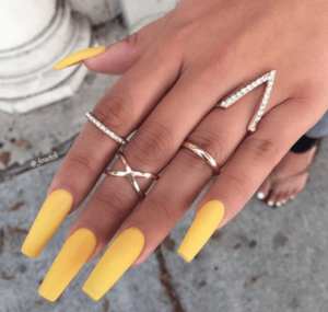 A woman's hand with yellow nails and rings, ready for a Quinceanera event