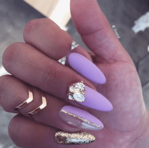 A person holding a purple and gold manicure for a Quinceanera
