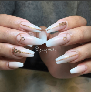 A woman with a manicure holding a pair of white and gold nails for a Quinceanera celebration.