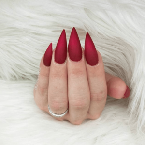 A Quinceanera themed image featuring a woman's hand with red stiletto nails