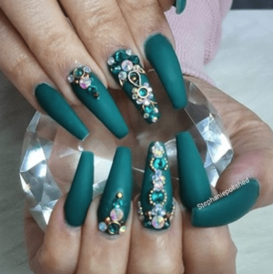 A person with a green manicure holding a crystal ring for a Quinceanera