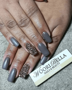 A woman's hand with a gray manicure and a silver glittered nail for a Quinceanera