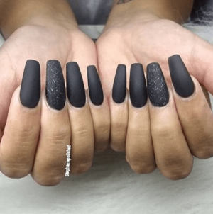 A person holding a pair of black nails, applying nail polish for a Quinceanera celebration.
