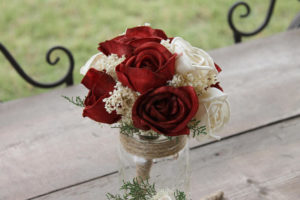A beautiful Quinceanera floral design featuring a vase filled with red and white roses on a wooden table