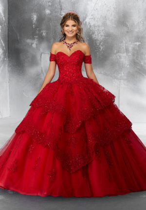 Quinceanera: A woman in a red ball gown posing for a picture, wearing a sweet sixteen sweet 16 dress Quinceañera dress.