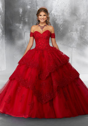 Quinceanera: A woman in a red ball gown posing for a picture, wearing a sweet sixteen sweet 16 dress Quinceañera dress.