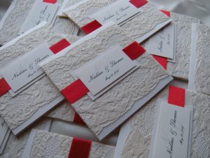 A pile of white and red Quinceanera cards in different shades of paper color.