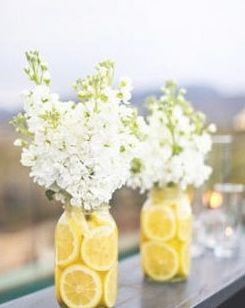 Table with lemon centerpiece ideas. The table features three vases filled with lemon slices and white flowers.